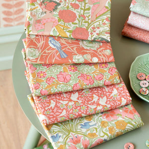 Stacks of colorful fabric on a table with a decorative plate and buttons.
