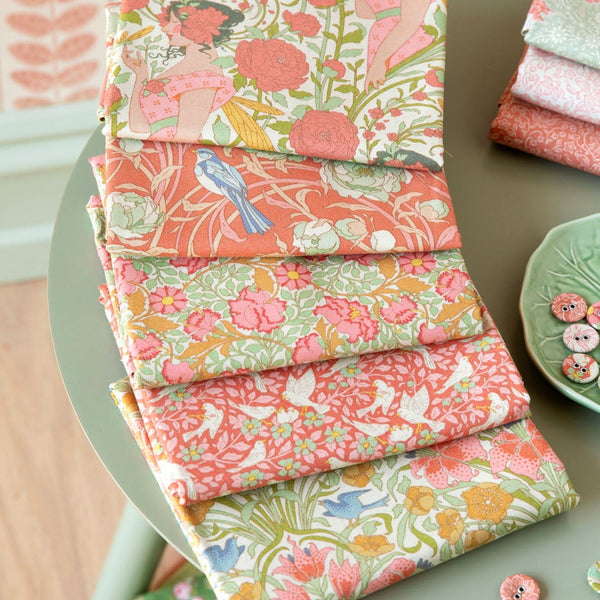 Stacks of colorful fabric on a table with a decorative plate and buttons.