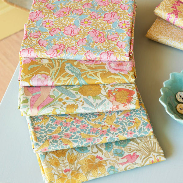 Stack of fabric swatches with floral patterns on a table.